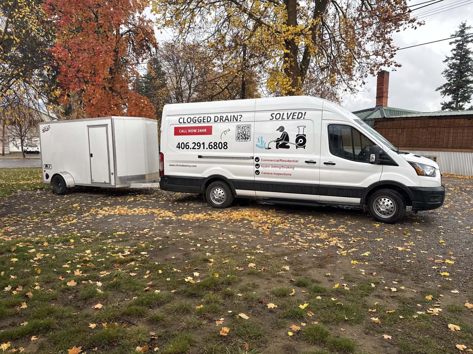 Chris's drain service van pulling his equipment trailer under fall trees